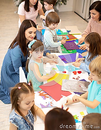 Prechool children working with paper under the supervision of teachers. Group of little children doing project in Stock Photo