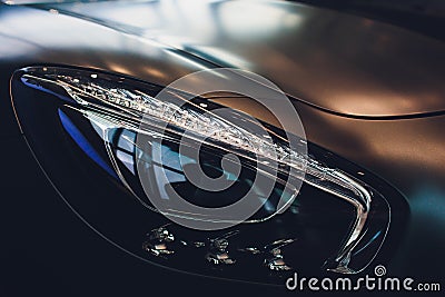 Predatory car headlight and hood of powerful sports grey car with blue glare. Stock Photo