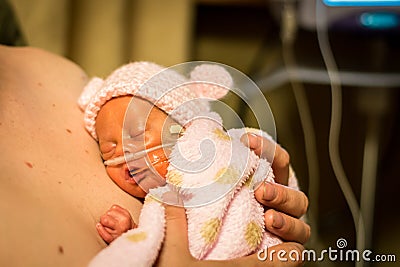 Preemie baby girl enjoying skin to skin with dad Stock Photo