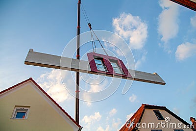 Prefabricated house part with two red windows is hoisted between two houses by the mobile crane for assembly Stock Photo