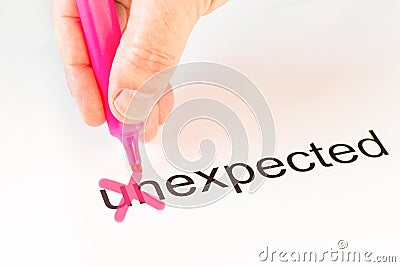The prefix `un` of the word unexpected is crossed out with a pink pencil by a hand Stock Photo