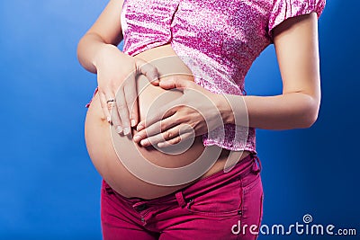 Pregnan woman in casual outfit cherish her belly. blue background Stock Photo