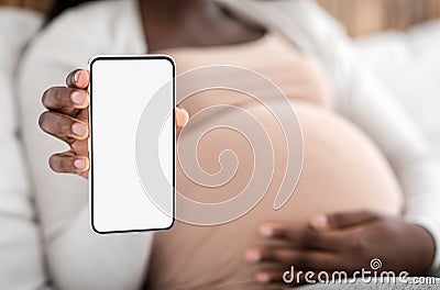 Pregnancy App. Black pregnant lady demonstrating smartphone with blank white screen Stock Photo