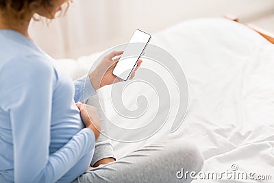 Pregnancy calendar app. Afro woman holding cellphone with blank screen Stock Photo