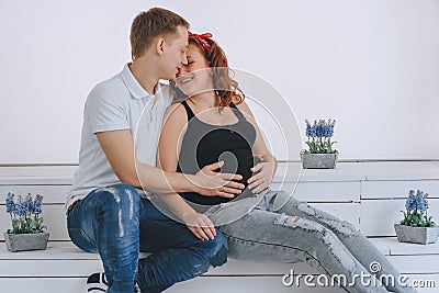 Pregnancy. A man kisses a pregnant woman. The husband keeps his hand on the belly wife. Future parents. Waiting for a Stock Photo