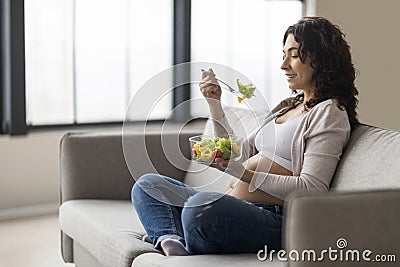 Pregnancy Nutrition. Young pregnant woman eating vegetable salad while relaxing at home Stock Photo