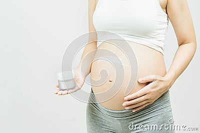 Pregnancy, people and maternity concept - Pregnant Skin Care. Woman Applying Cream On Belly Stock Photo