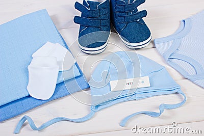 Pregnancy test with positive result and clothing for newborn, expecting for baby Stock Photo