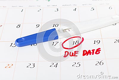 Pregnancy test with positive result lying on calendar background Stock Photo