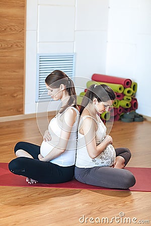 Pregnancy Yoga, Fitness concept. Portrait of two attractive young pregnant yoga models working out indoor Stock Photo