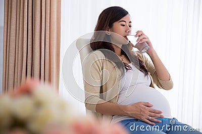 Pregnant asian woman drinking a glass of water Stock Photo