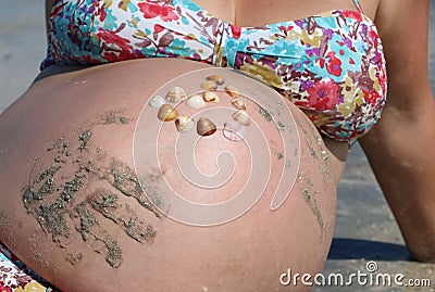 Pregnant belly with shell heart and hand prints Stock Photo