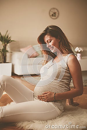 Pregnant brunette woman touching her belly. Stock Photo