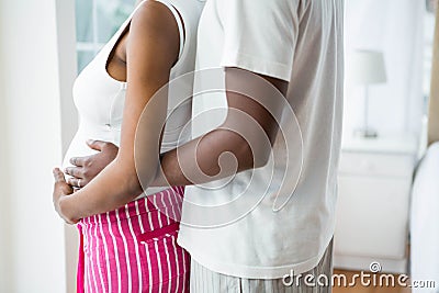 Pregnant couple embracing in bedroom Stock Photo