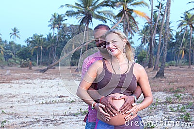 Pregnant couple walking on the beach Stock Photo