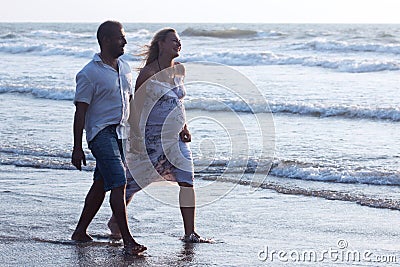 Pregnant couple walking on the beach Stock Photo