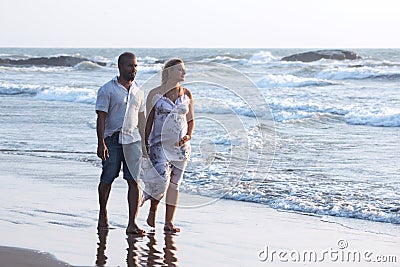 Pregnant couple walking on the beach Stock Photo