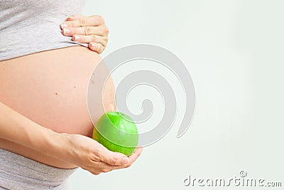 Pregnant girl holding a green apple. nutrition during pregnancy. Vitamins and pregnancy. Source of iron, pregnant anemia. Stock Photo