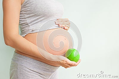 Pregnant girl holding a green apple. nutrition during pregnancy. Vitamins and pregnancy. Source of iron, pregnant anemia. Stock Photo