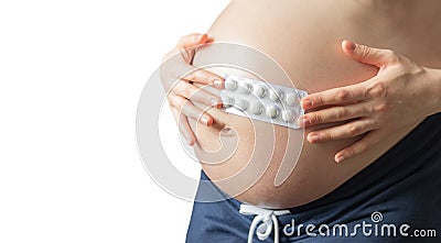 pregnant girl holding pills on the background of pregnant belly, the concept of taking drugs and vitamins Stock Photo