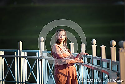 Pregnant girl walking along the promenade. Portrait of a girl with a stomach. A young girl in a summer dress walking along the Stock Photo