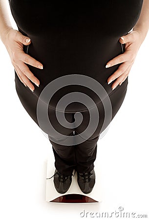 Pregnant lady weighing oneself, focus on belly Stock Photo