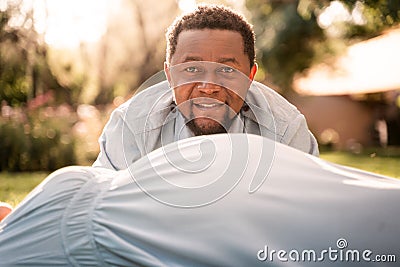 Pregnant Latina woman and African man couple in a lush green sunlit park Stock Photo