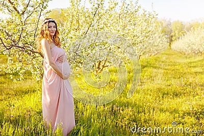 Pregnant mother in the summer meadow with spring white flowers. Stock Photo