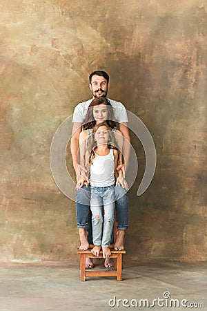 Pregnant mother with teen daughter and husband. Family studio portrait over brown background Stock Photo