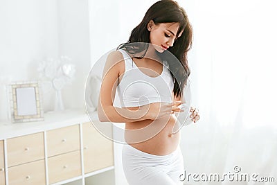 Pregnant Skin Care. Beautiful Woman Applying Cream On Belly Stock Photo