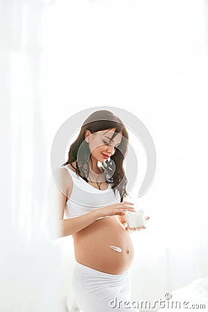 Pregnant Skin Care. Beautiful Woman Applying Cream On Belly Stock Photo