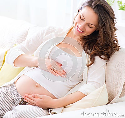 Pregnant smiling woman sitting on a sofa Stock Photo