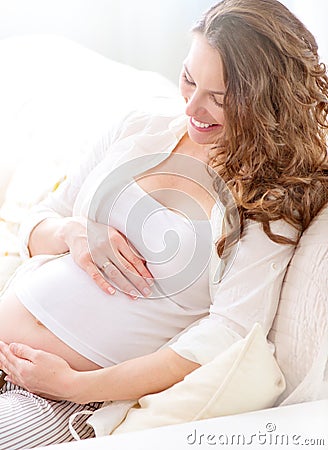 Pregnant smiling woman sitting on a sofa Stock Photo