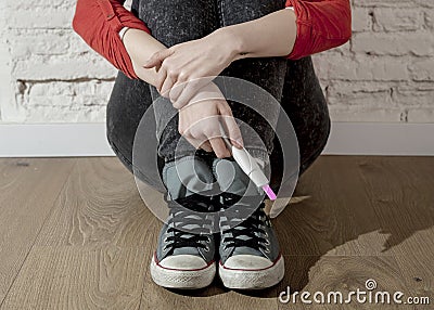 Pregnant teenager girl or young desperate woman holding positive pink pregnancy test Stock Photo