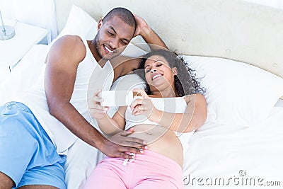 Pregnant wife showing smartphone to husband Stock Photo