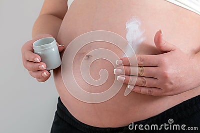 Pregnant woman applying cream on her belly for healing and skin elasticity Stock Photo