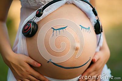 Pregnant woman belly closeup with smiling funny face drawing on Stock Photo