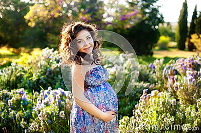 Pregnant woman in the blooming spring garden. Pregnancy and maternity shoot woman. Stock Photo