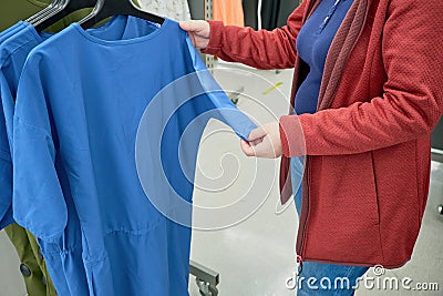 Pregnant woman chooses loose blue T-shirt in store to buy. Hands close up Stock Photo