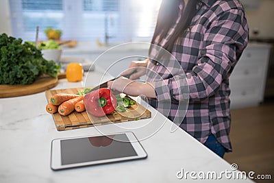 Pregnant woman chopping vegetables in kitchen Stock Photo