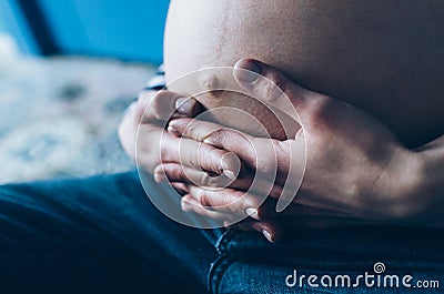 Pregnant woman cuddling belly in bedroom at home just before the labor and childbirth, selective focus Stock Photo