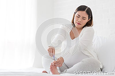 Pregnant woman cutting nails feet by nail clipper Stock Photo