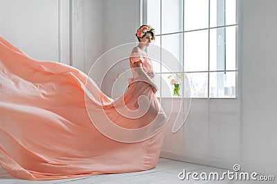 Pregnant woman dancing in pink evening dress flying on wind. Waving fabric, fashion shot. Stock Photo