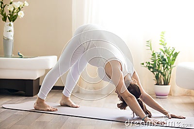 Pregnant woman doing downward facing dog yoga pose at home Stock Photo