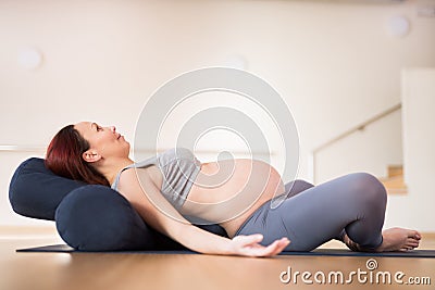 Pregnant woman is engaged in yoga. Reclined Goddess Pose or Supta Baddha Konasana Stock Photo
