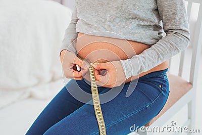 Pregnant woman feeling curious measuring waistline Stock Photo