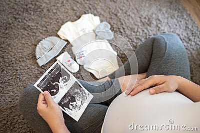 Pregnant woman feeling happy : Close up of pregnant woman holding ultrasound scan on her tummy Stock Photo