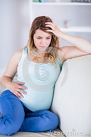 Pregnant woman having headache on couch Stock Photo