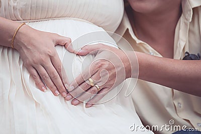 Pregnant woman and her husband making hand heart shape together Stock Photo