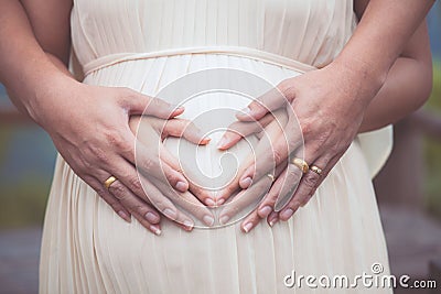 Pregnant woman and her husband making hand heart shape together Stock Photo